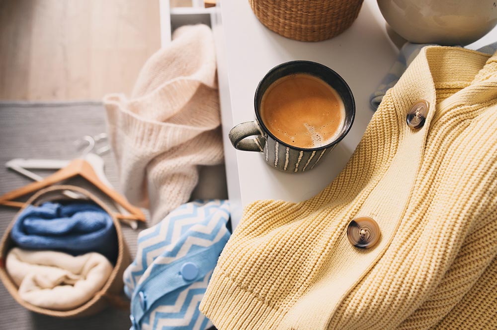 Coffee and laundry folded on bed