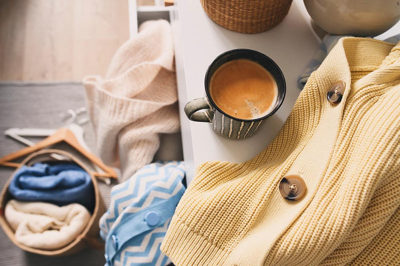 Coffee and laundry folded on bed laundry tips for new moms