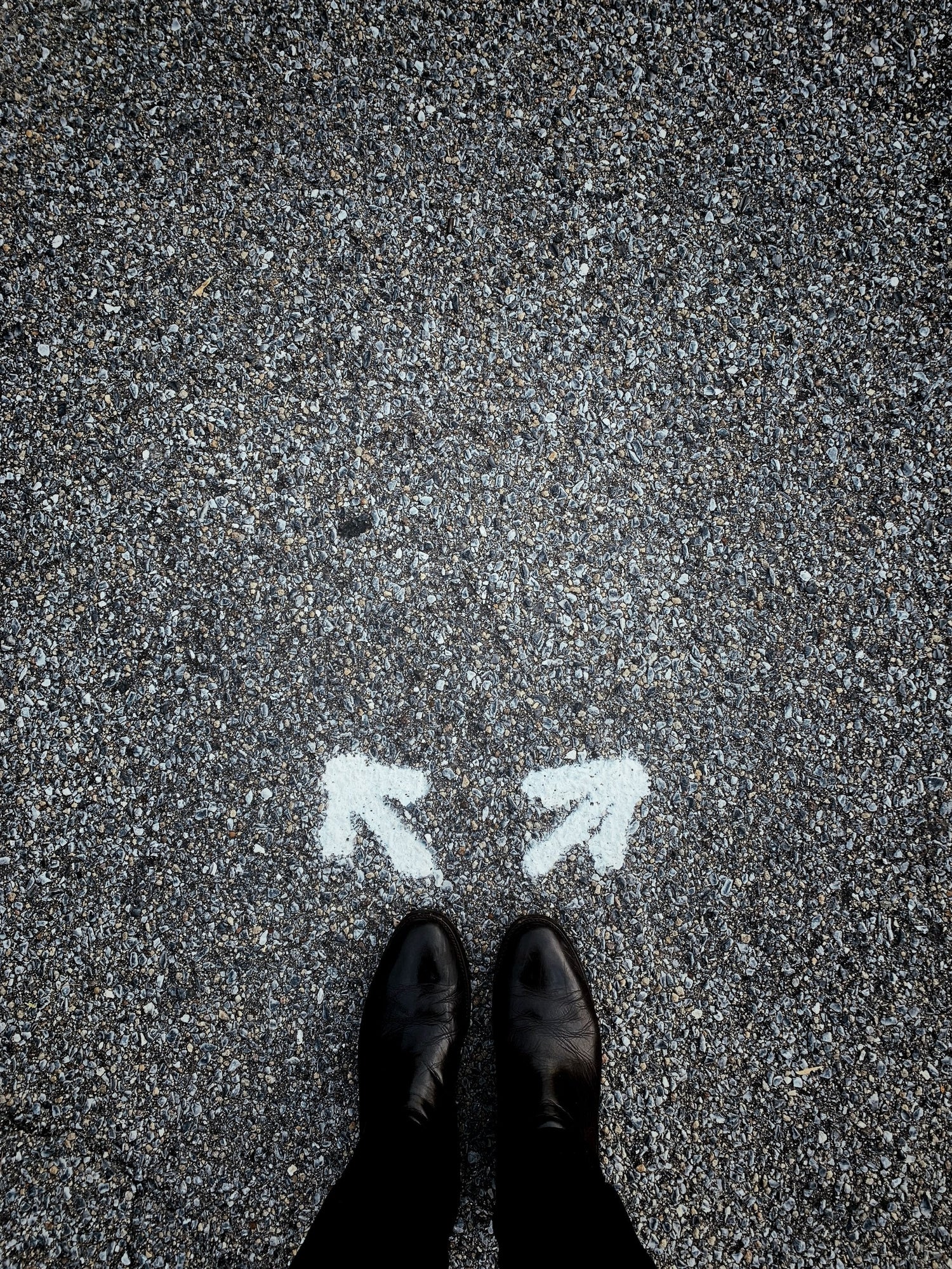 Feet near arrows on pavement path