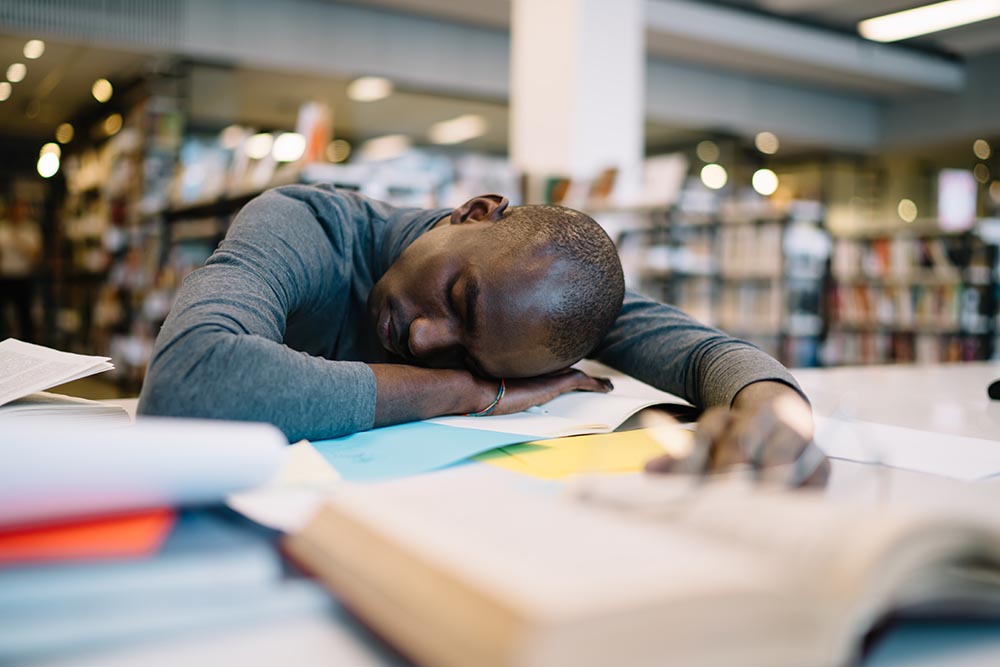 Person resting on desk with head down, feeling tired