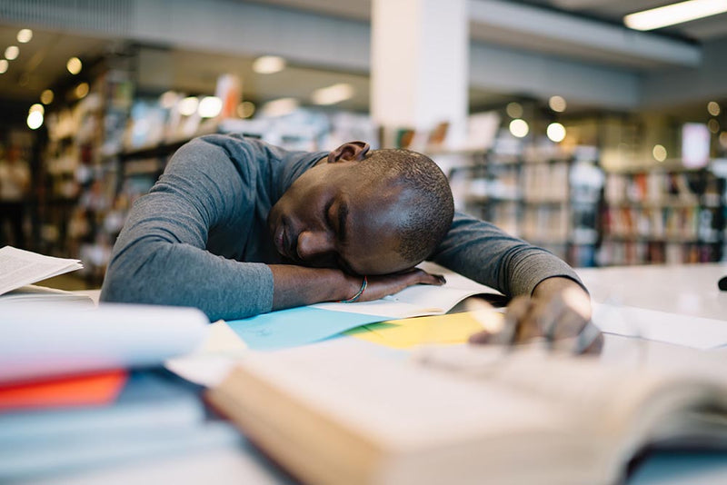 college sleep tips Person resting on desk with head down, feeling tired