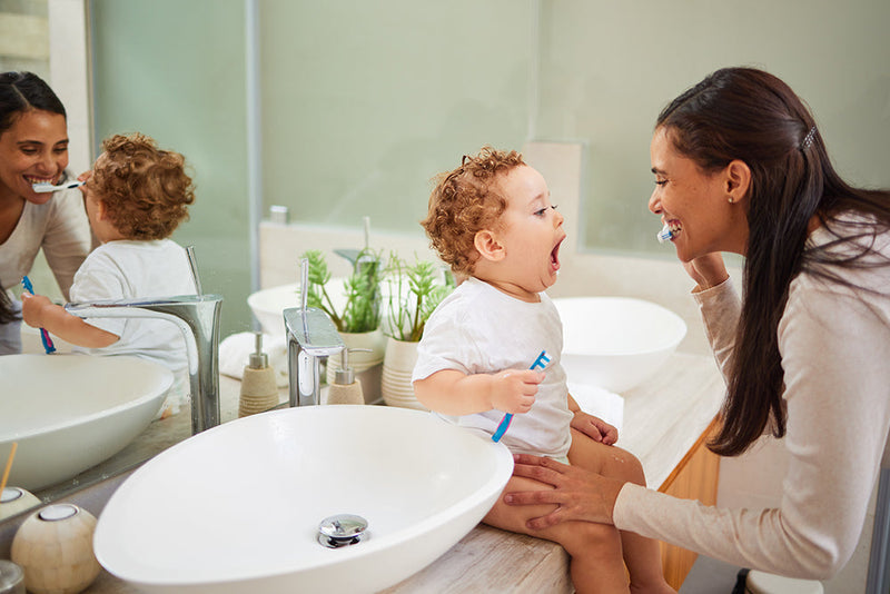 Mother taking care of newborn at sink self-care for new moms