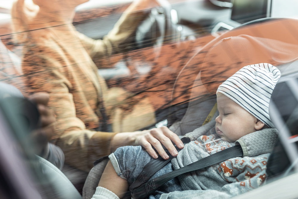 Mother adjusting baby’s seat in car