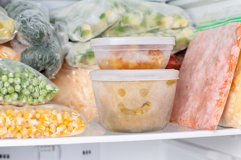 Frozen meal containers in freezer shelf Dinner Hacks for New Moms