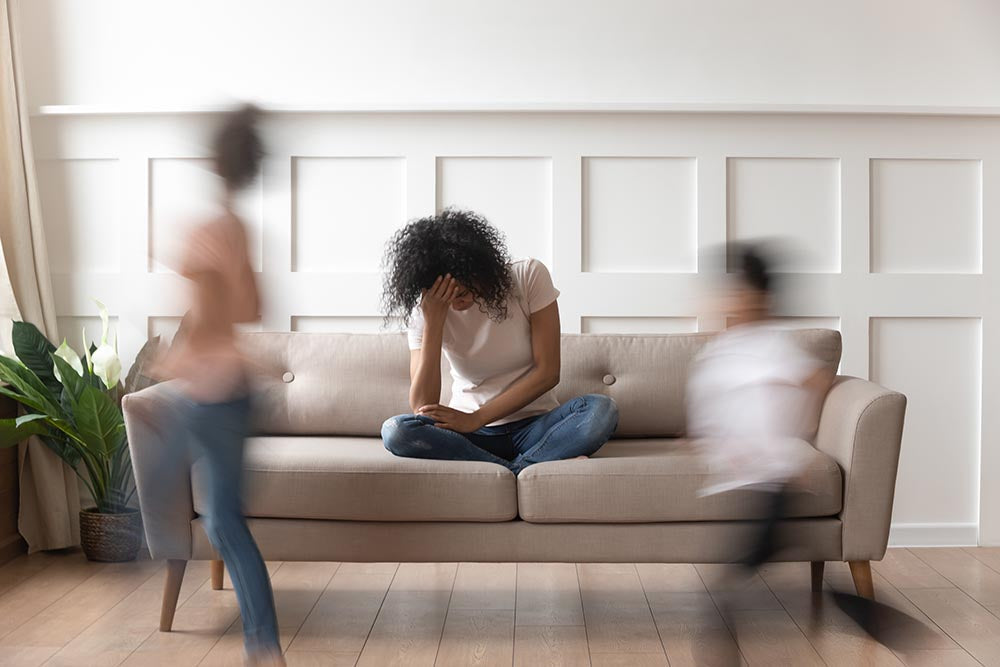 Mother on couch with moving children