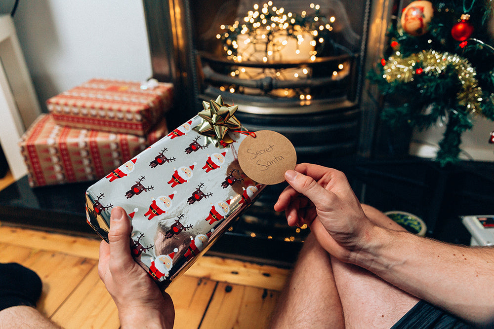 Person handing wrapped holiday gift holiday gift guide