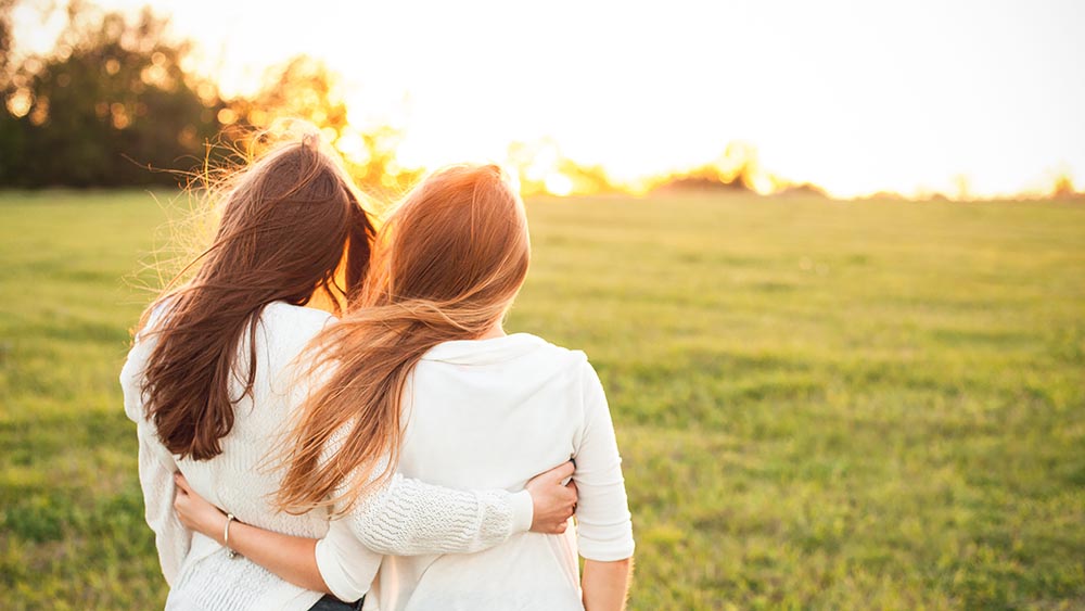 Two women sitting outside, hugging peacefully