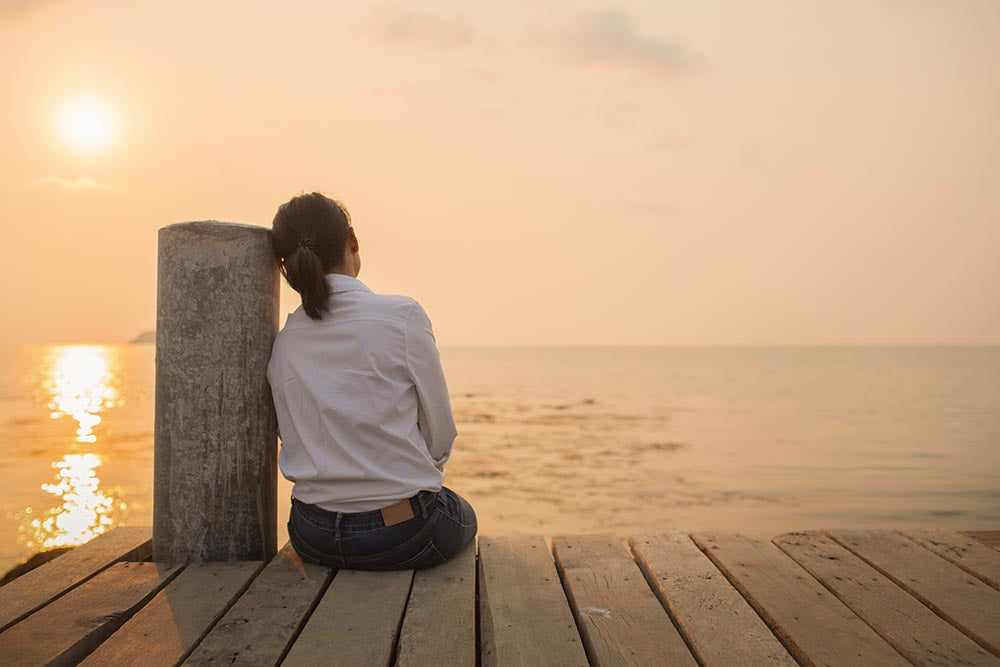 Person sitting alone on wooden dock acts of kindness and disappointment