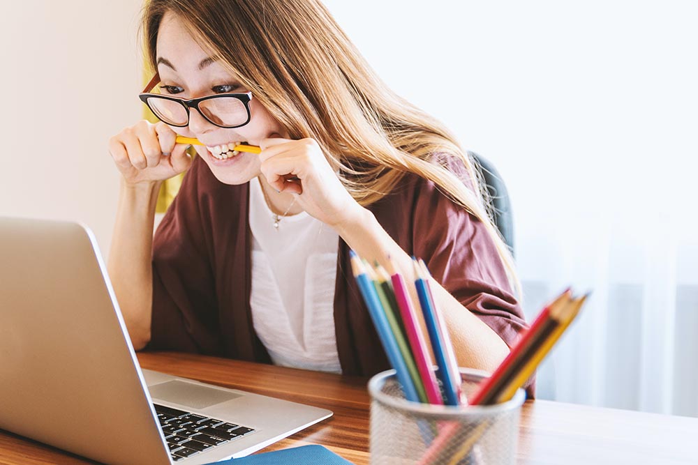Smiling student using laptop and pencils