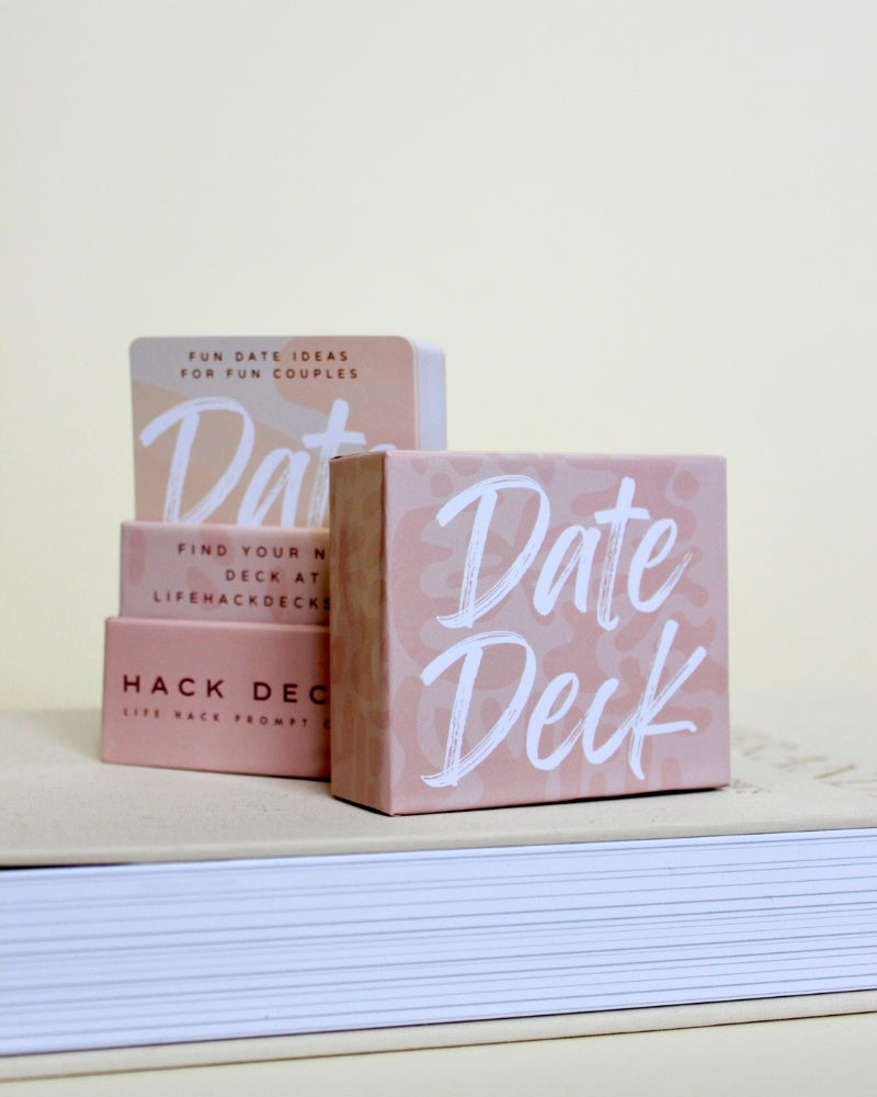Pink 'Date Deck' product packaging on a light surface with a white background